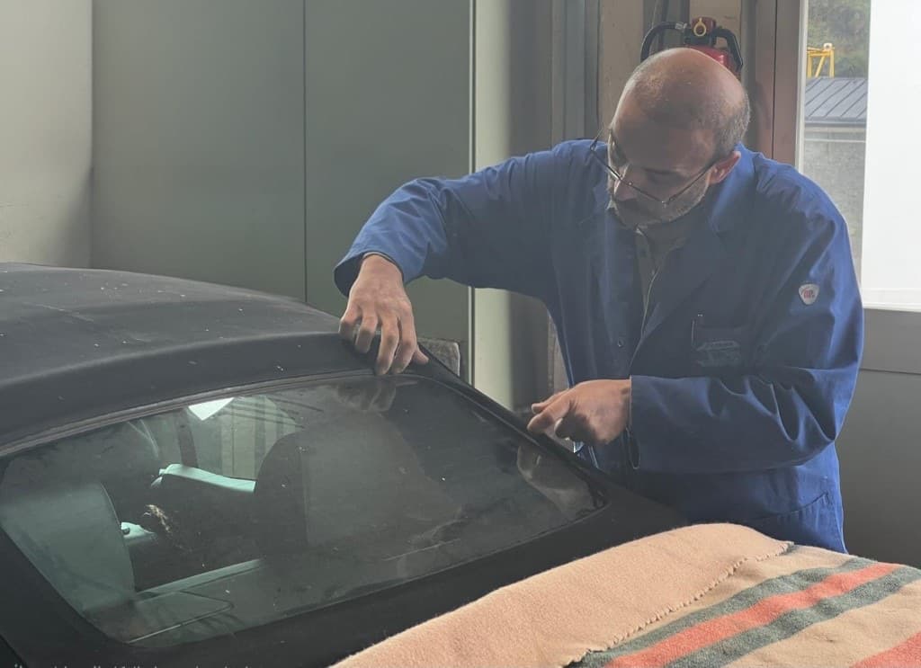 Sattlerarbeit an einem schwarzen Cabrio-Verdeck in der Werkstatt