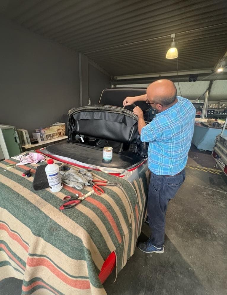 Arbeit am Verdeck eines roten Cabrios in der Werkstatt
